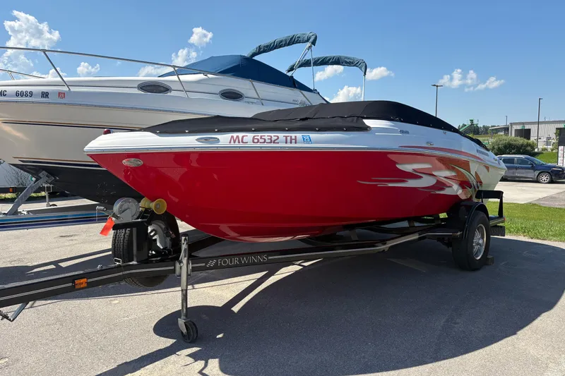 Slide: The Image of 2011 Four Winns H190SS boat with red hull on trailer, parked outdoors. - 0
