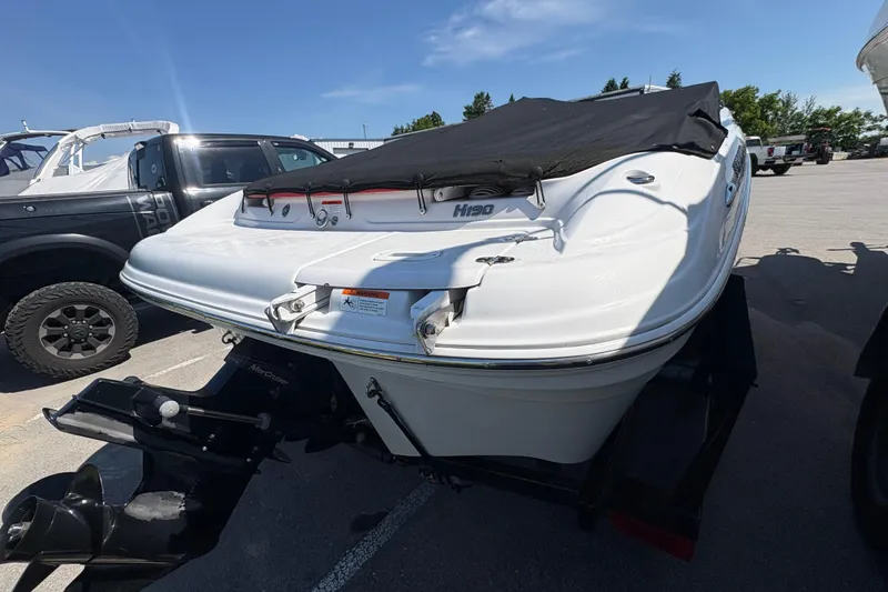 Slide: The Image of 2011 Four Winns H190SS boat with cover, parked on a trailer in a lot. - 2