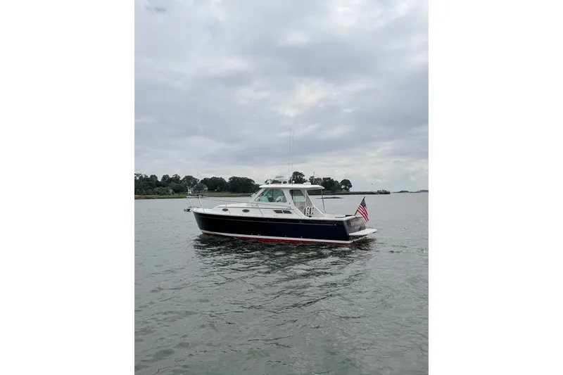 Slide: The Image of 2006 Back Cove 29 boat on calm water with American flag, overcast sky. - 8