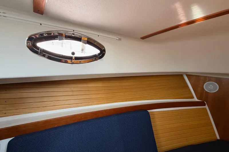 Slide: The Image of Interior of a 2006 Back Cove 29 boat, featuring a porthole and wooden paneling. - 29