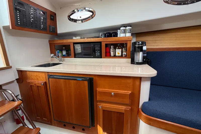 Slide: The Image of 2006 Back Cove 29 yacht interior with kitchenette, featuring sink, microwave, and seating area. - 23