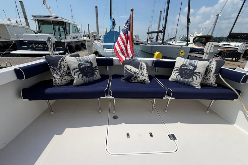 Slide: The Image of 2006 Back Cove 29 boat interior with navy seating, nautical pillows, and American flag at marina. - 48