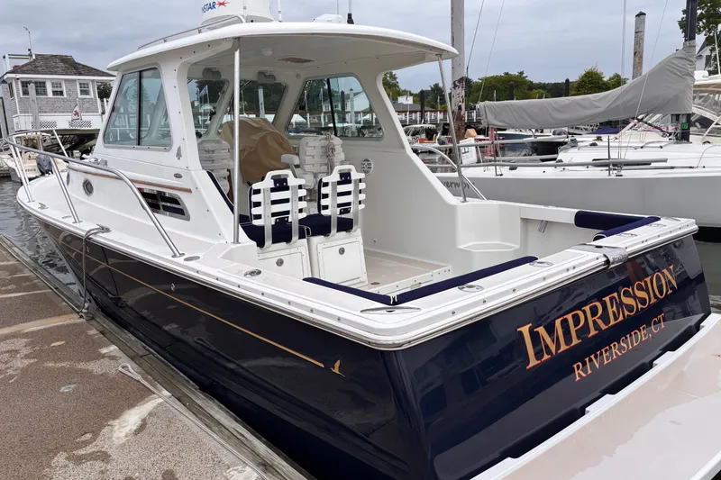 Slide: The Image of 2006 Back Cove 29 boat docked, featuring sleek design and "Impression" name on the stern. - 50