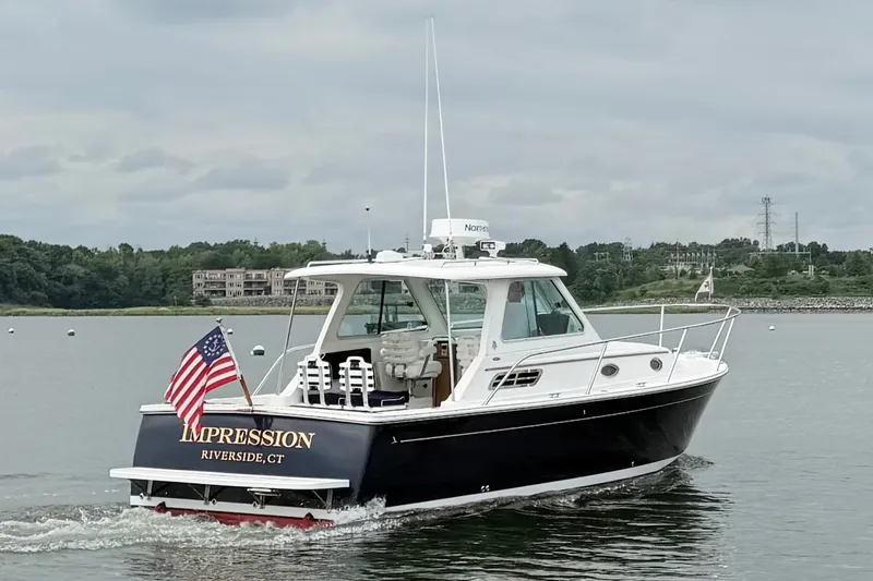 Slide: The Image of 2006 Back Cove 29 boat cruising on a calm lake with American flag. - 10
