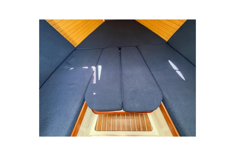 Slide: The Image of 2006 Back Cove 29 interior cabin with blue cushions and wooden accents. - 28