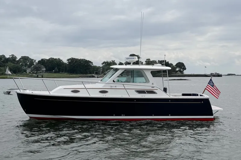 Slide: The Image of 2006 Back Cove 29 boat on calm water with American flag, overcast sky. - 49