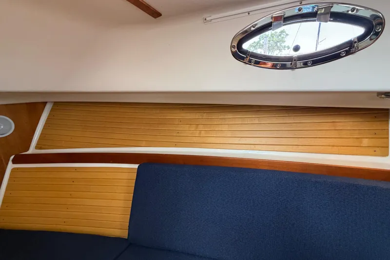 Slide: The Image of Interior of a 2006 Back Cove 29 boat, featuring wood paneling and a porthole window. - 30