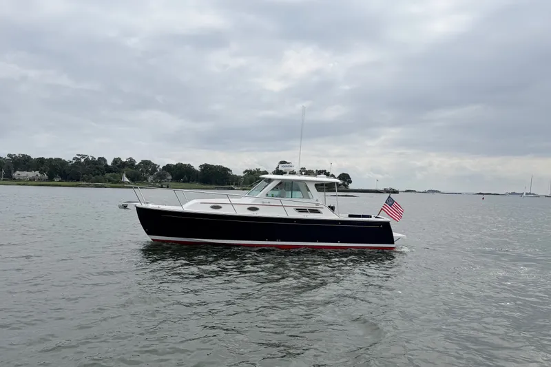Slide: The Image of 2006 Back Cove 29 boat on calm water with American flag, overcast sky. - 9