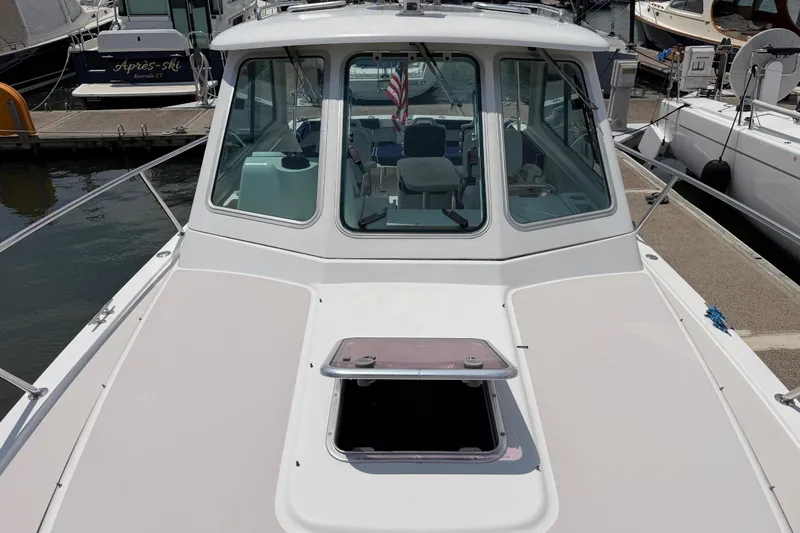 Slide: The Image of 2006 Back Cove 29 boat docked, featuring a spacious deck and cabin windows. - 13