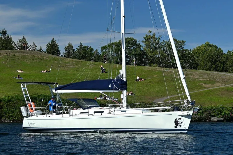 The Image of Sailing yacht J Boats J/130 (1994) cruising near a grassy shoreline under a clear blue sky. - 2