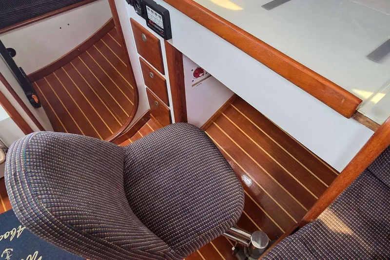 Slide: The Image of Interior of 1994 J Boats J/130, featuring wood paneling and a cushioned chair. - 48