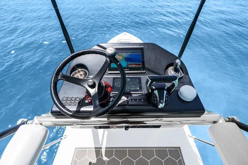 Slide: The Image of The image shows the helm of a 2023 Contender 44 ST boat on calm water. - 25