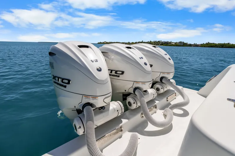 Slide: The Image of Three powerful outboard engines on a boat in calm, blue waters with an island in the background. - 33