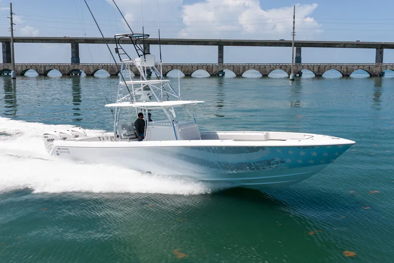 Slide: The Image of A 2023 Contender 44 ST speeds across the water, with a bridge in the background. - 44