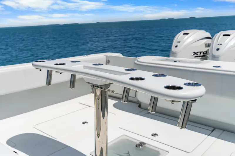 Slide: The Image of The image shows the stern of a 2023 Contender 44 ST boat with rod holders and engines. - 32