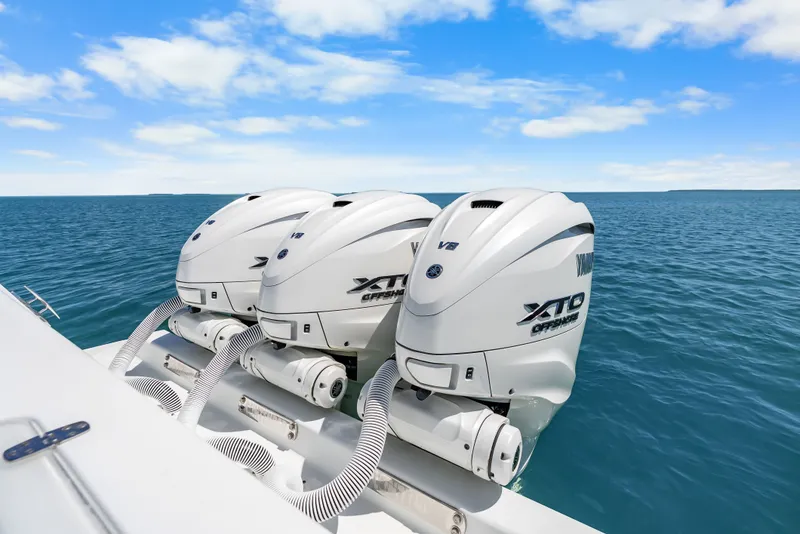 Slide: The Image of Three powerful outboard engines on a boat in calm, blue waters under a clear sky. - 35