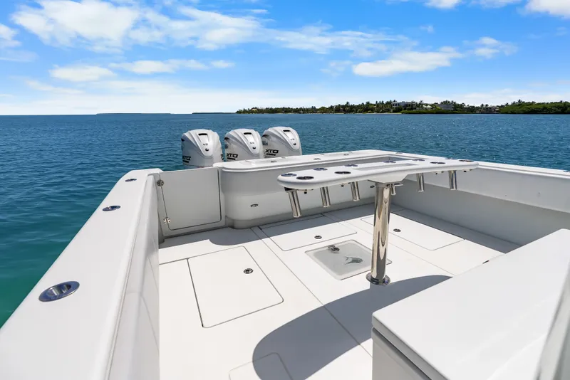 Slide: The Image of The image shows the stern of a Contender 44 ST boat with three outboard engines on calm water. - 29