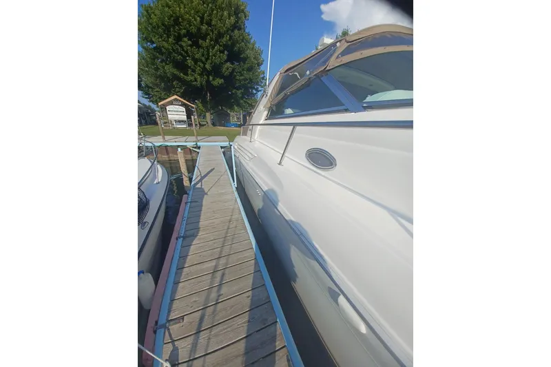 Slide: The Image of 1996 Sea Ray 450 Sundancer docked beside a wooden pier under a clear sky. - 5