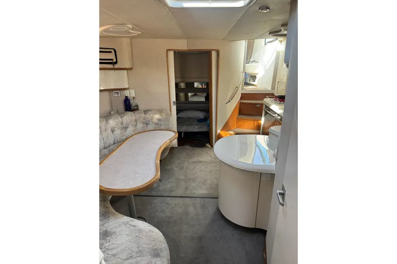 Slide: The Image of Interior of 1996 Sea Ray 450 Sundancer yacht with seating, table, and kitchenette. - 21