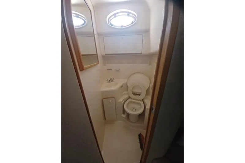 Slide: The Image of Bathroom interior of a 1996 Sea Ray 450 Sundancer yacht, featuring a compact toilet and sink. - 23