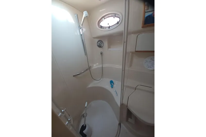 Slide: The Image of Bathroom interior of 1996 Sea Ray 450 Sundancer yacht, featuring shower and porthole window. - 17