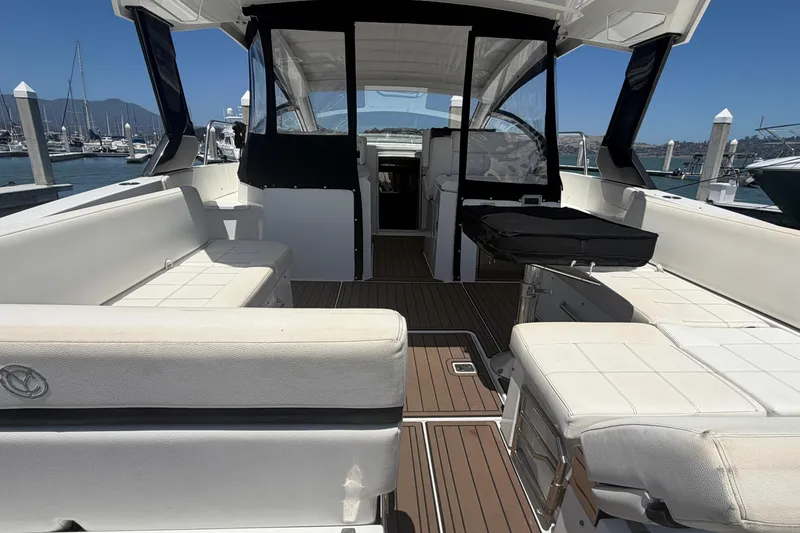 Slide: The Image of 2015 Cruisers 390 yacht interior with white seating and wooden flooring at a marina. - 5