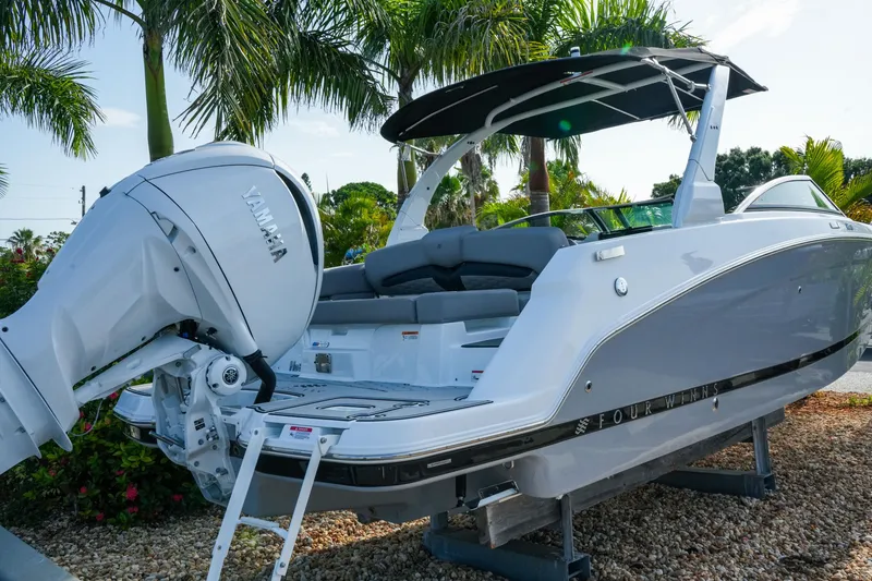 Slide: The Image of 2027 Four Winns HD8 OB boat with Yamaha outboard motor, parked on gravel, surrounded by palm trees. - 4
