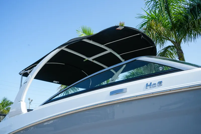 Slide: The Image of 2027 Four Winns HD8 OB boat with canopy, set against a clear blue sky and palm trees. - 3
