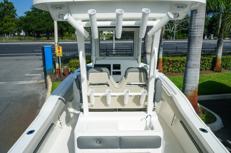 Slide: The Image of 2027 Key West 249 FS boat with rod holders and seating, parked near palm trees. - 20