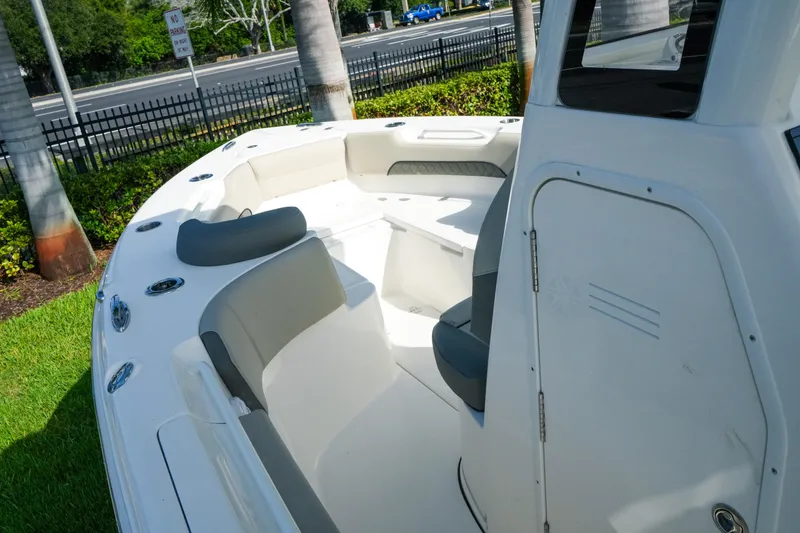Slide: The Image of 2027 Key West 249 FS boat interior with seating, parked on grass near a road. - 29