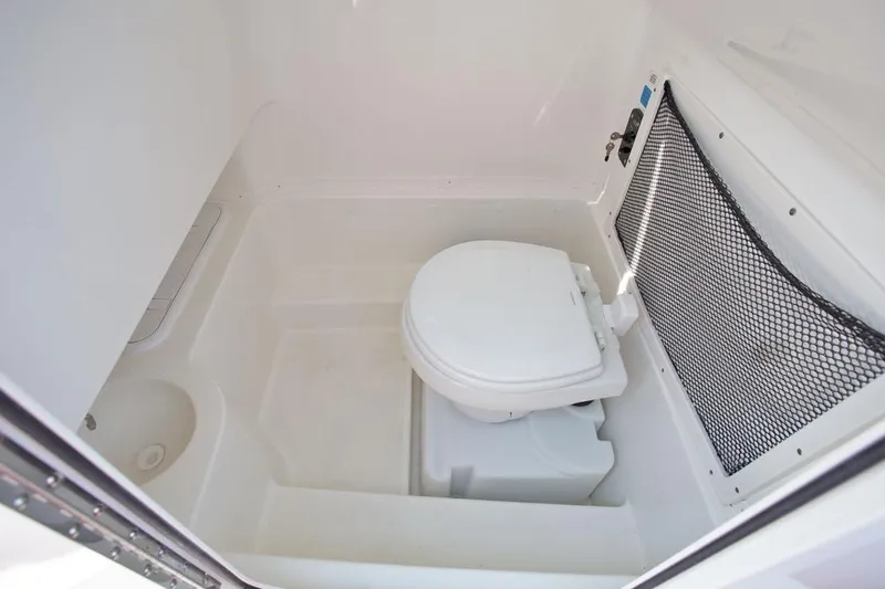 Slide: The Image of Manufacturer Provided Image: 2020 NauticStar 2602 Legacy boat interior with marine toilet and storage net. - 13