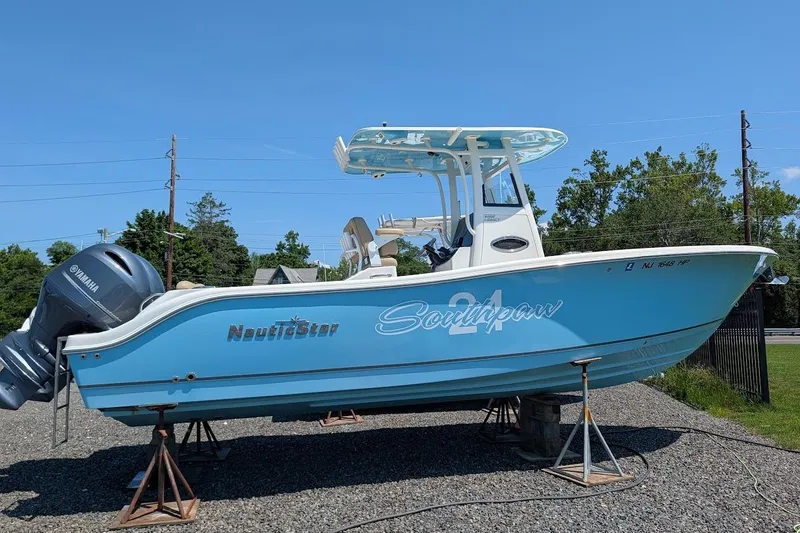 The Image of 2020 NauticStar 2602 Legacy boat on stands, featuring Yamaha engine, blue hull, and "Southpaw" name. - 0