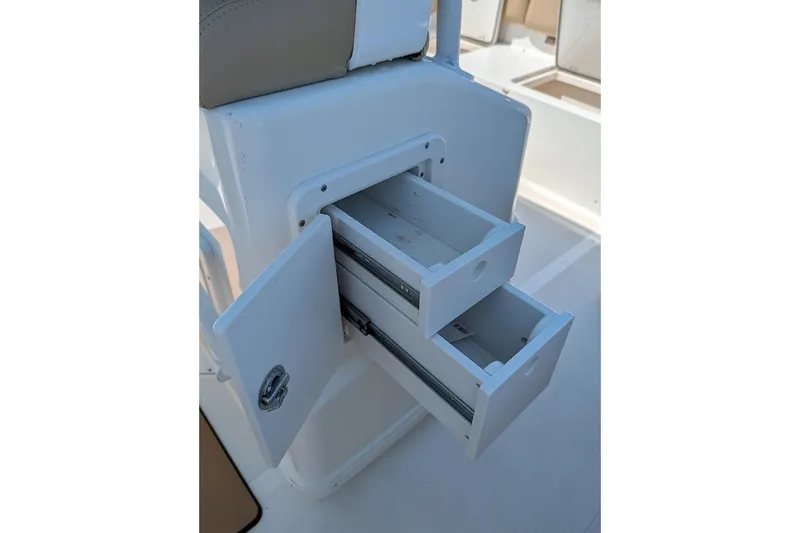 Slide: The Image of 2020 NauticStar 2602 Legacy boat storage drawers open on deck. - 17