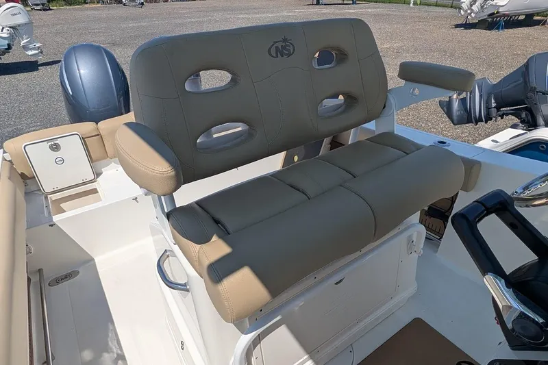 Slide: The Image of 2020 NauticStar 2602 Legacy boat seating and helm area, featuring beige upholstery. - 14
