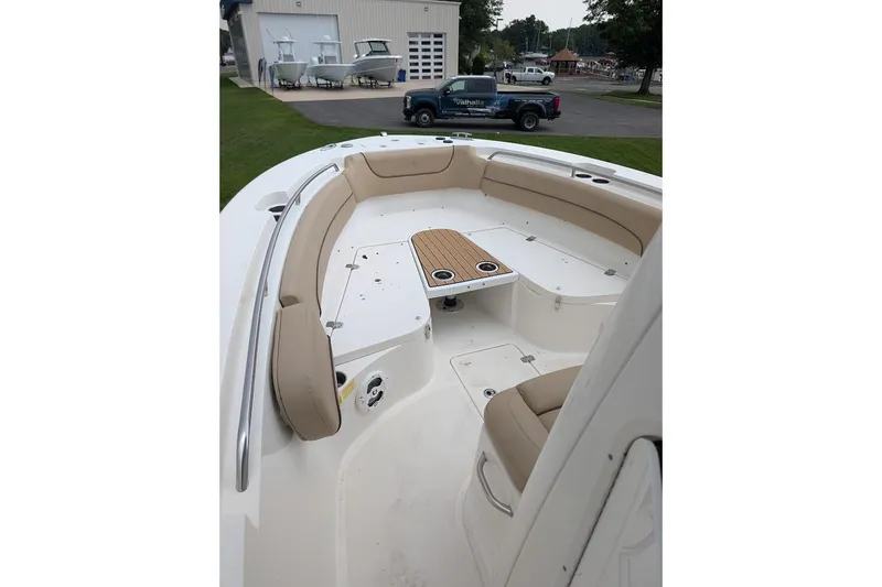 Slide: The Image of 2020 NauticStar 2602 Legacy boat interior with beige seating and wooden table. - 10