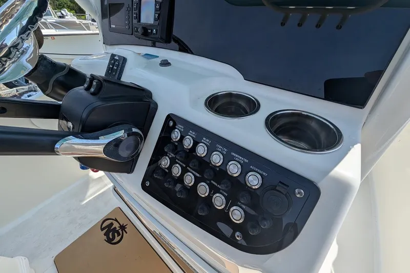 Slide: The Image of Control panel of a 2020 NauticStar 2602 Legacy boat with switches and cup holders. - 8