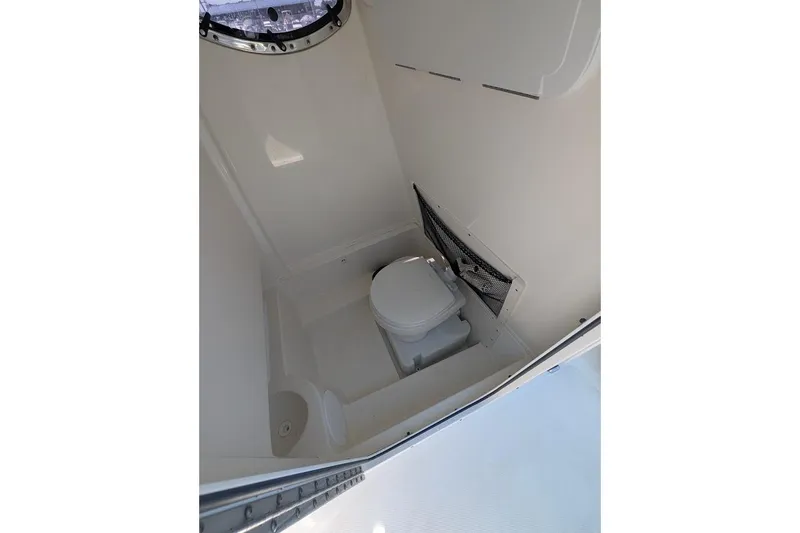 Slide: The Image of 2020 NauticStar 2602 Legacy boat interior bathroom with toilet and storage net. - 19
