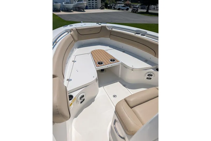 Slide: The Image of 2020 NauticStar 2602 Legacy boat interior with beige seating and wooden table. - 24