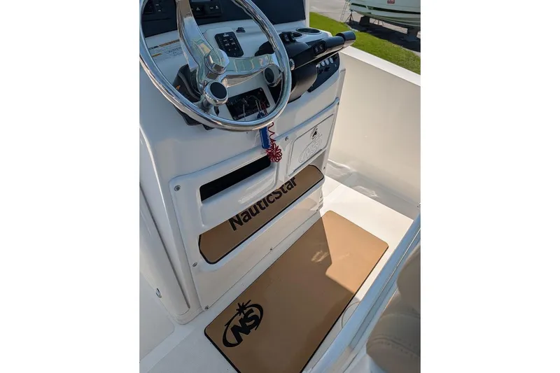 Slide: The Image of 2020 NauticStar 2602 Legacy boat helm with steering wheel and branded mat. - 13