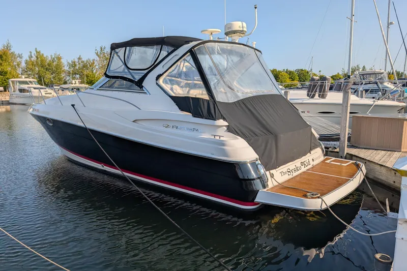 Slide: The Image of 2005 Regal Commodore 3560 IO boat docked in a marina, featuring sleek design and covered cockpit. - 2