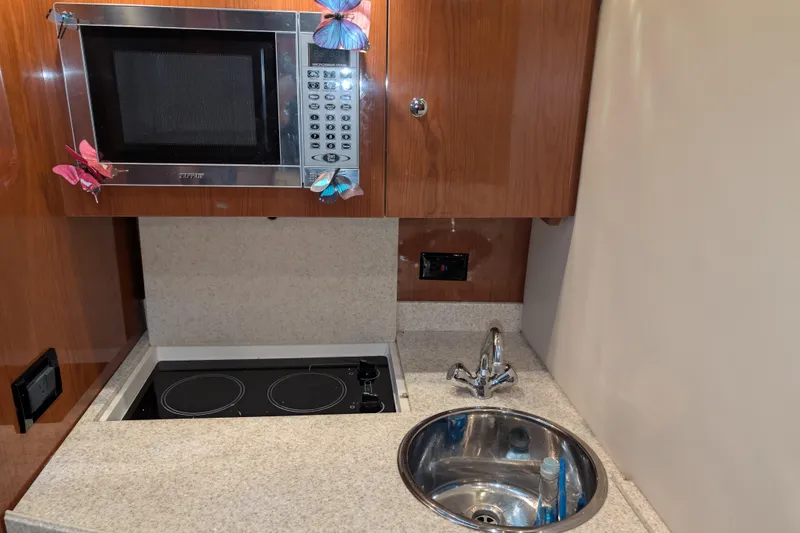 Slide: The Image of Compact kitchen area in a 2005 Regal Commodore 3560 IO boat with microwave and sink. - 12