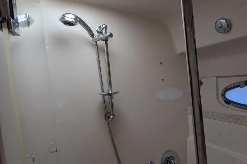 Slide: The Image of Shower area inside 2005 Regal Commodore 3560 IO boat, featuring chrome fixtures and porthole window. - 17