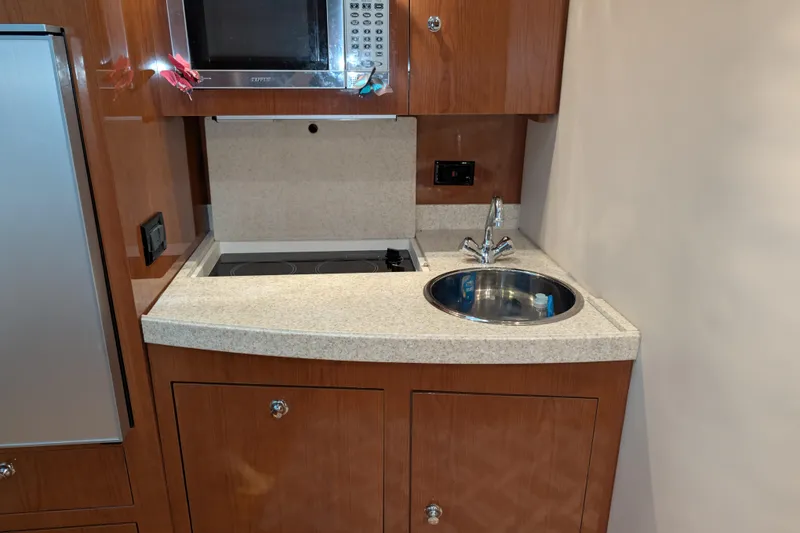 Slide: The Image of Compact kitchen area in a 2005 Regal Commodore 3560 IO boat, featuring sink and microwave. - 13