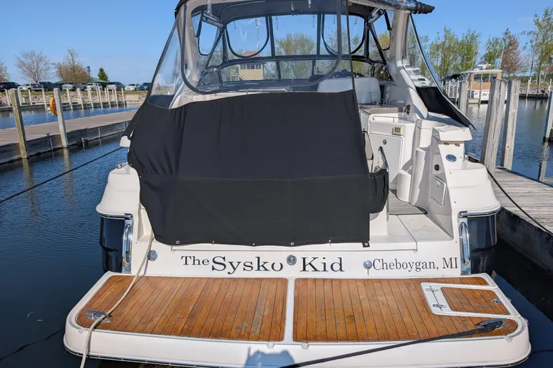 Slide: The Image of 2005 Regal Commodore 3560 IO boat docked, rear view with wooden deck and black cover. - 3