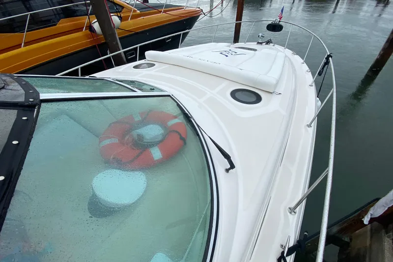 Slide: The Image of 2004 Sea Ray 340 Sundancer yacht with lifebuoy on deck, docked in rainy weather. - 9