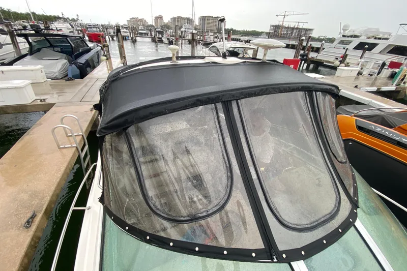 Slide: The Image of 2004 Sea Ray 340 Sundancer docked at marina, featuring a black canopy and clear windows. - 13