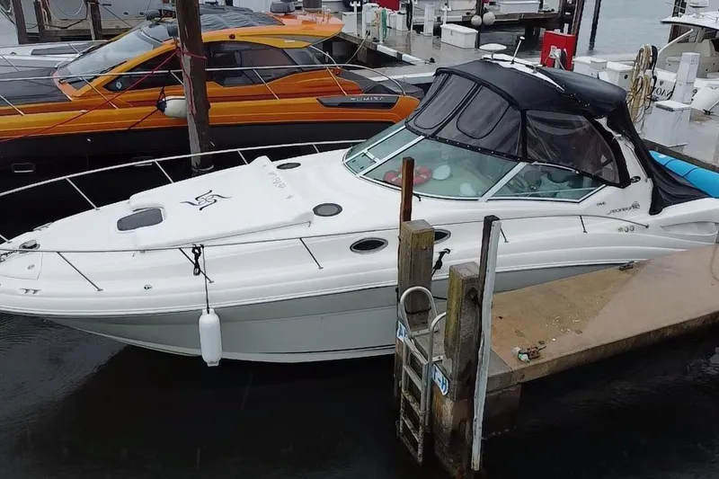 Slide: The Image of 2004 Sea Ray 340 Sundancer docked at marina, featuring sleek white design and black canopy. - 1