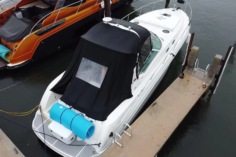 Slide: The Image of 2004 Sea Ray 340 Sundancer docked, featuring a black canopy and blue floatation devices. - 24