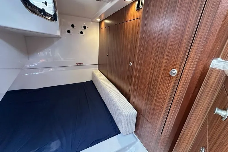 Slide: The Image of 2022 Pursuit OS 325 Offshore cabin interior with wood paneling and blue bedding. - 29