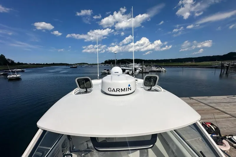 Slide: The Image of 2022 Pursuit OS 325 Offshore boat with Garmin radar, docked under a blue sky. - 53
